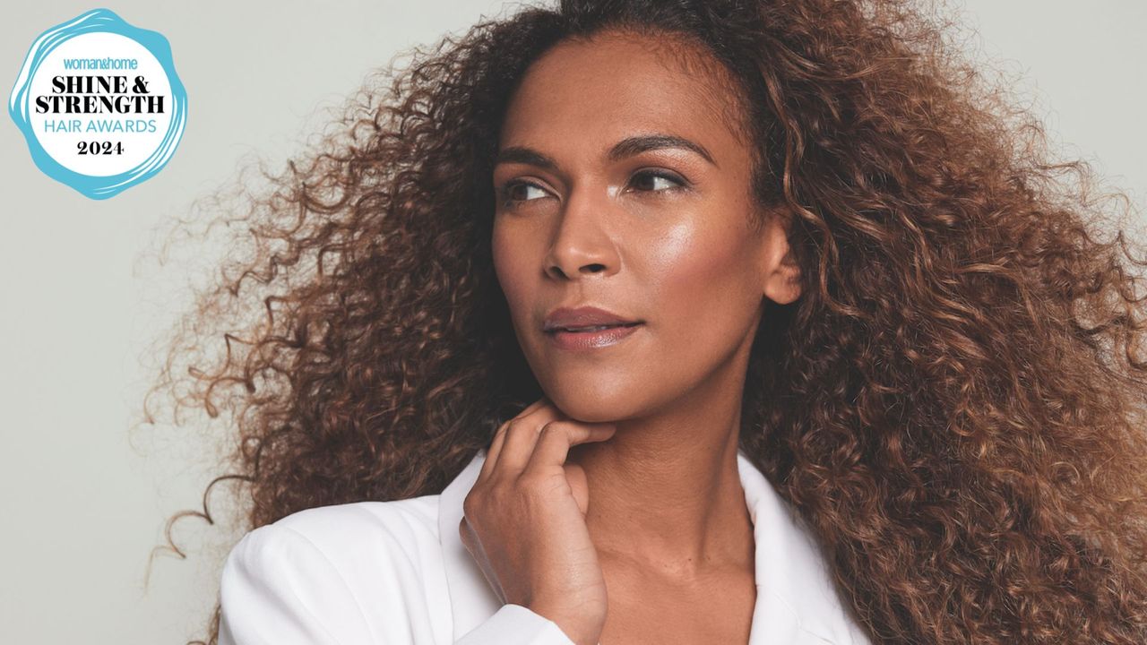 A close-in shot of a woman with tight coily hair with a logo of the 2024 woman&amp;home hair awards