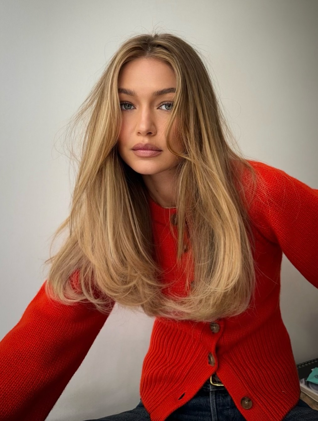 Photo of Gigi Hadid with a blowout wearing a red sweater