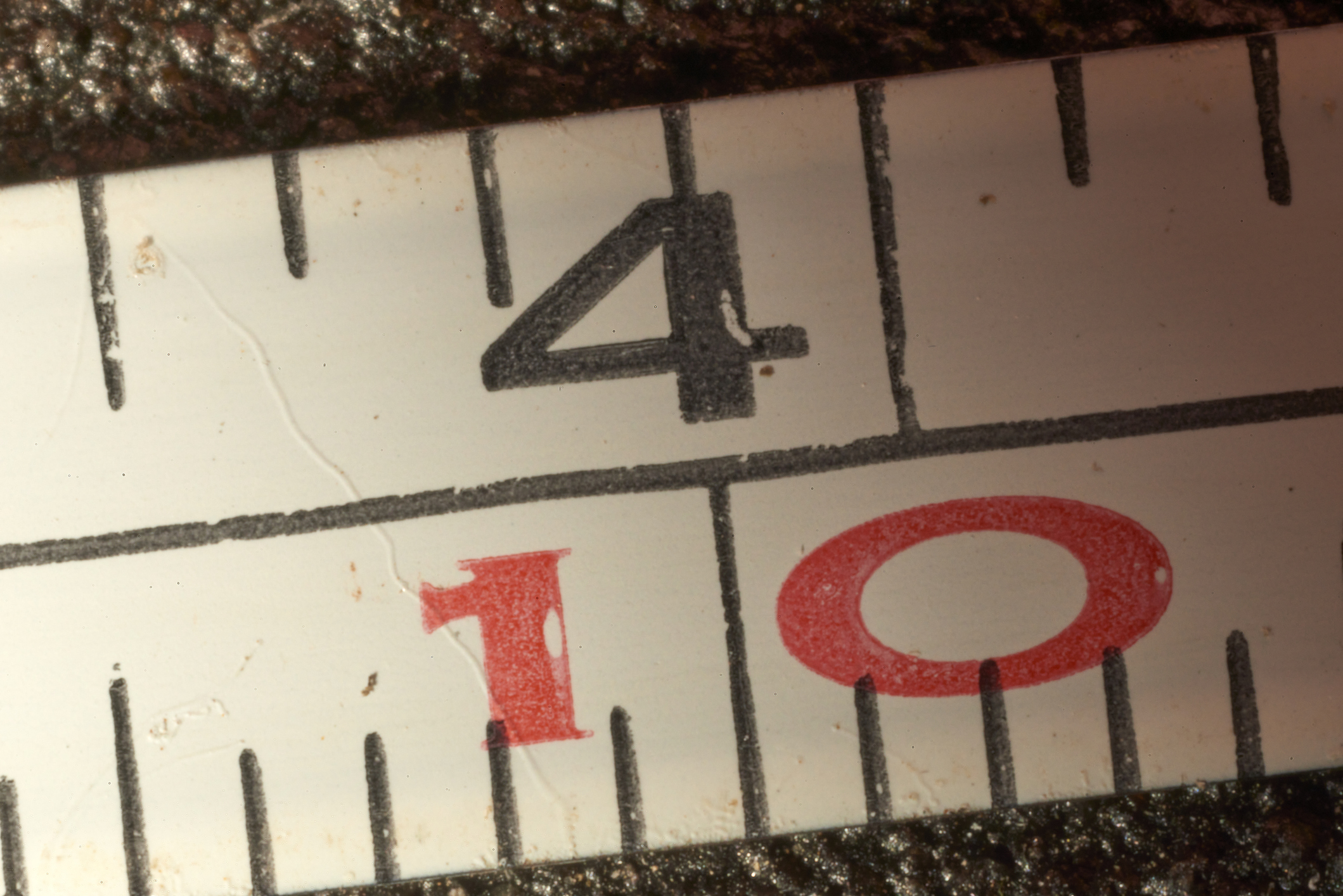 Close-up view of a measuring tape highlighting the four-inch mark with a precise measurement of one-tenth of an inch, emphasizing accuracy and precision in measuring length.