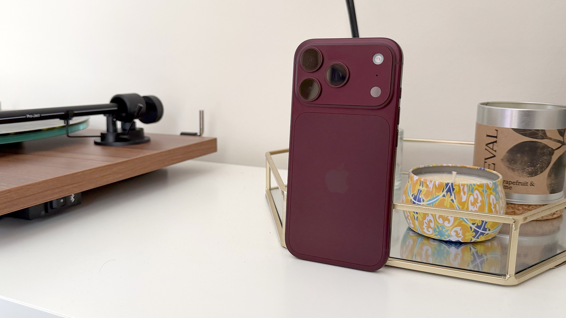 Apple iPhone 18 Pro smartphone leaning up against glass tray next to turntable, rear of device showing camera array