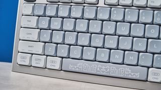 The NuPhy Nos75 mechanical keyboard on a stone surface with a blue background