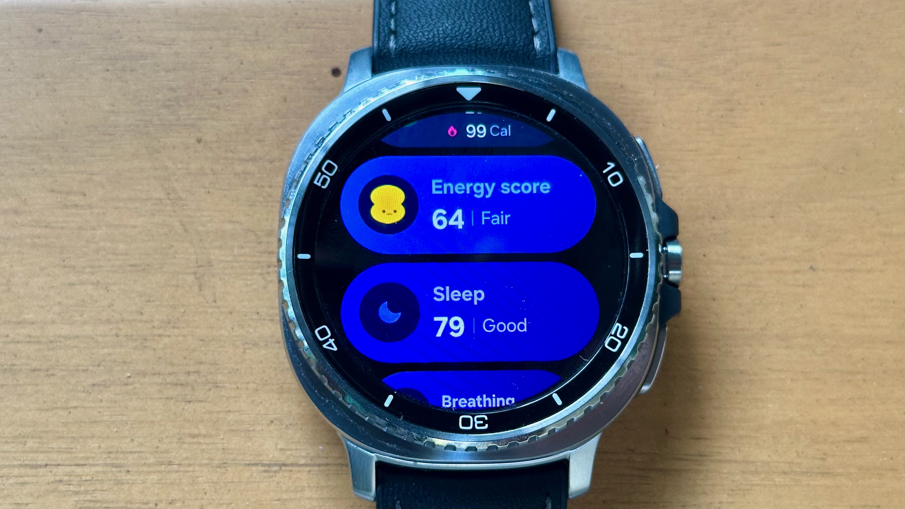 Close-up of the Samsung Galaxy Watch 8 Classic showing the Health tile with the user's Energy Score (64 / Fair) and Sleep score (79 / Good).