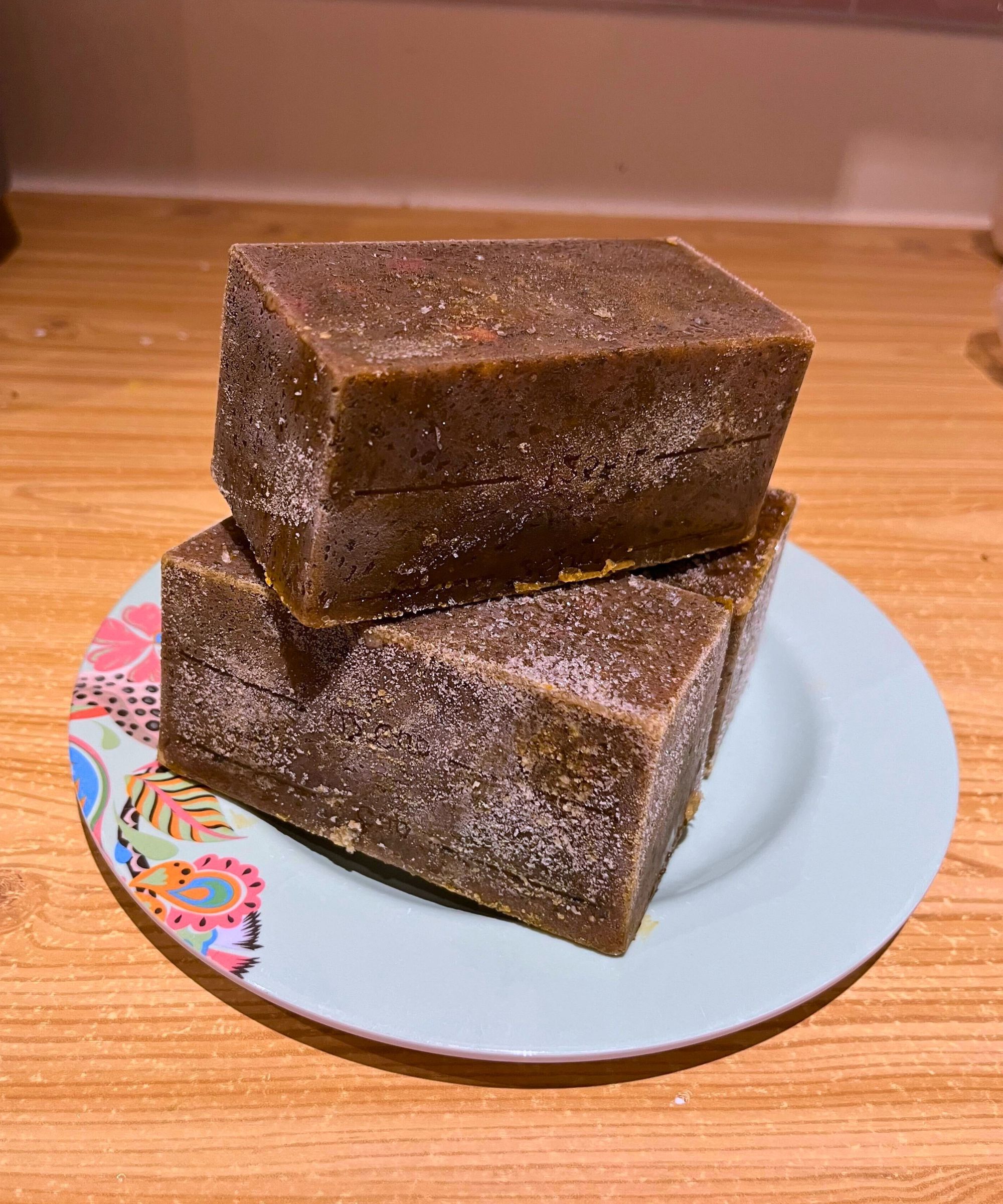 Multiple stacked blocks of deep green frozen Persian herby lamb stew (ghormeh sabzi) on a side plate