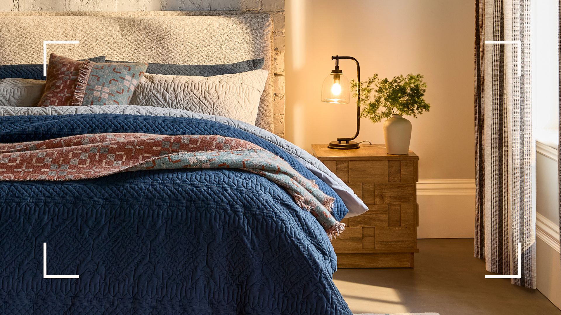 Bedroom with a bedside table and lamp with layered bedding dressing the bed