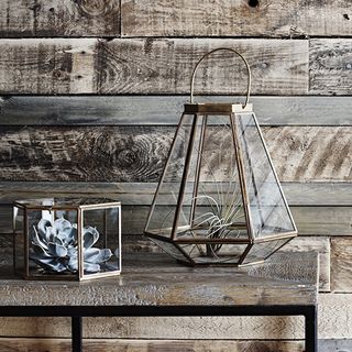 wooden table with hexagonal glass lantern and plant in it