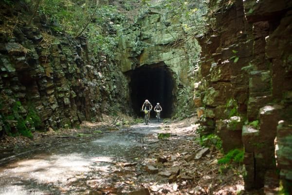Alex Grant (Cannondale) leads a Jamis rider out of the Poe Paddy tunnel on Trans-Sylvania&rsquo;s speedy dirt road oriented Coburn stage.