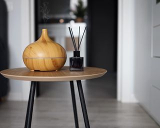An electric and reed diffuser on round wooden table