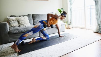 Woman working out with dumbbell in living room of home