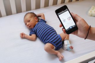 A baby wears the Owlet baby monitor on his ankle.