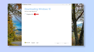 A screenshot of the Windows 10 media creation tool, with a red arrow pointing at the progress indicator. 