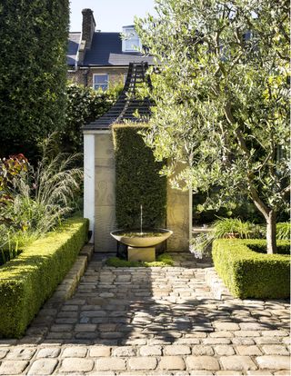 A garden with a cobbled path and neat shrubs
