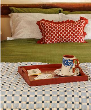 cottage bedroom with rustic wooden beams decorated for christmas with red and green bedding and a tray on the bed