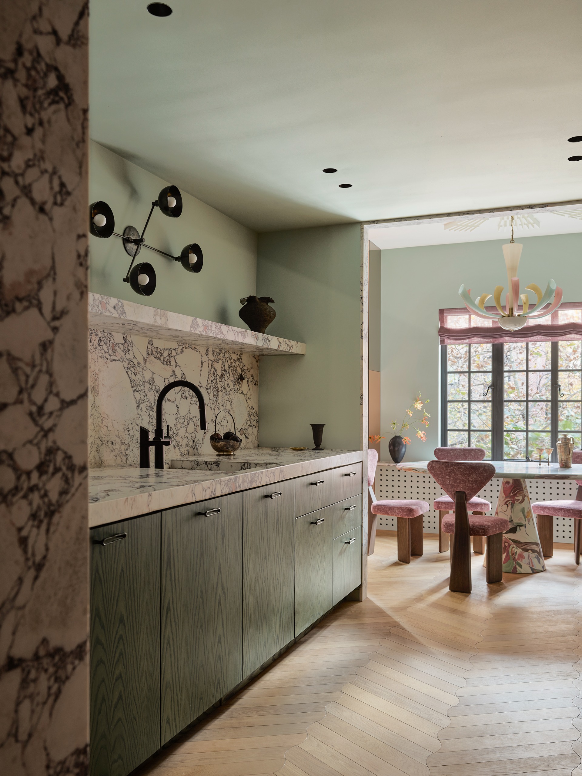 mint green kitchen with marble counters and a chandelier used as a wall light above the sink