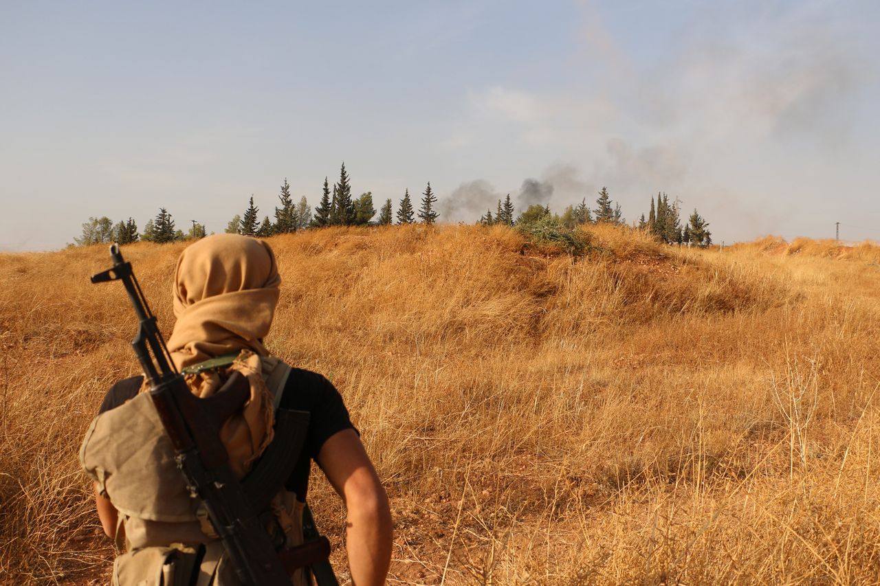 A Syrian rebel watches smoke from a battle near Aleppo