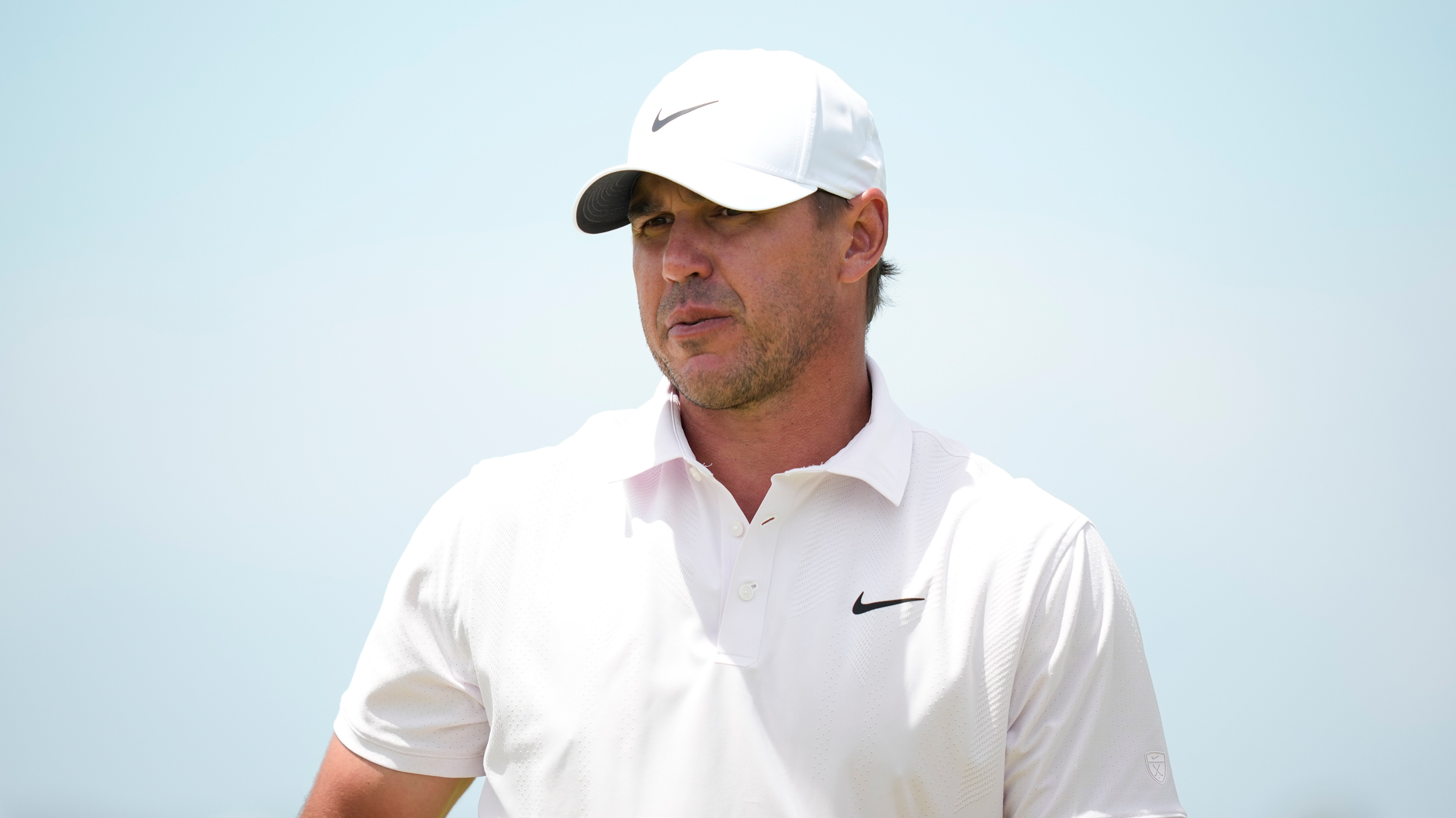 Brooks Koepka from the chest up wearing a white polo and white cap