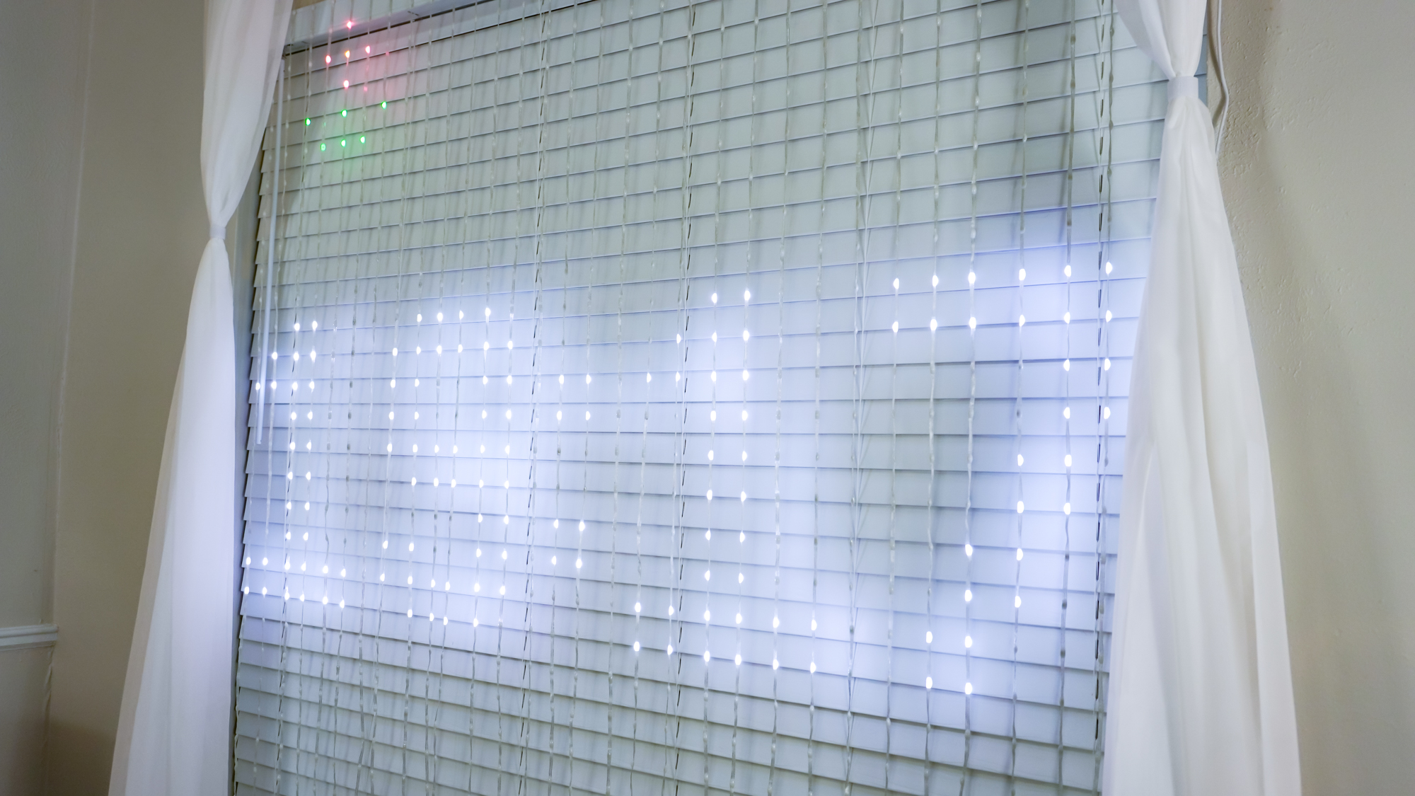 A close up of the Govee Curtain Lights Pro displaying a digital clock and the weather as an icon