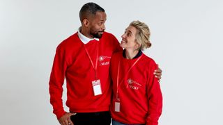 Choir Master Mark De-Lisser and Vicky McClure stand side-by-side in bright red jumpers