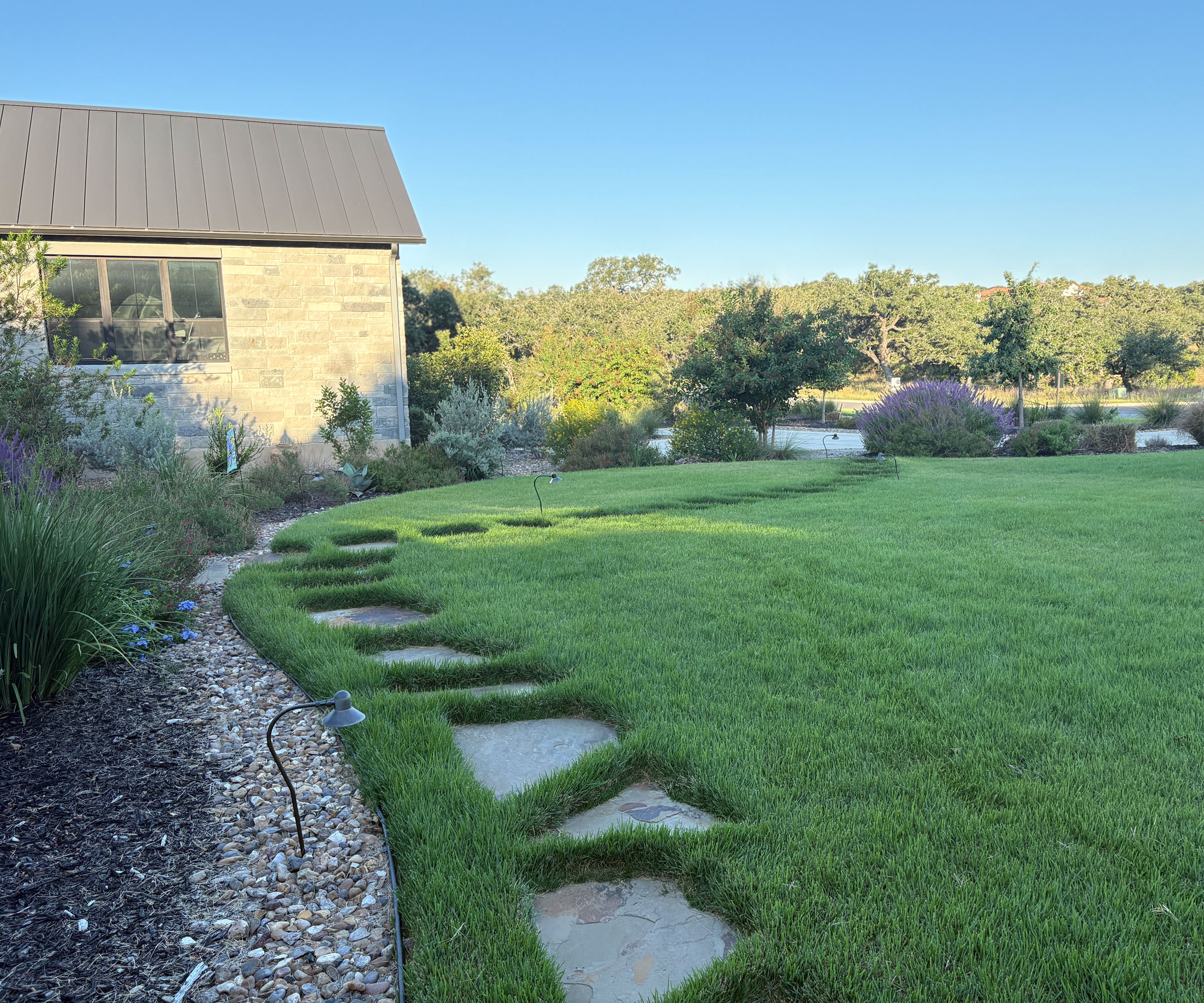 curving flagstone path cutting through lawn with gravel border