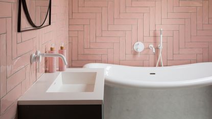 Pink bathroom with white bathtub and sink with black accents 