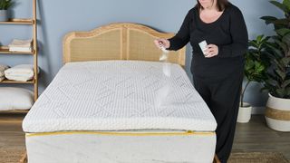 A woman sprinkling baking soda over a mattress topper