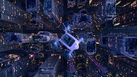 An illustration shows a flying car with four rotors flying over a tall city skyline