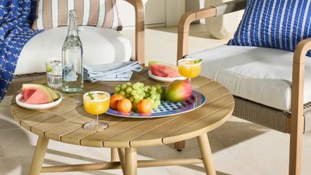 Outdoor patio table and chairs styled with assorted serveware, fresh fruit, and table linens.