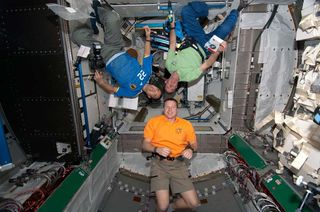 Shuttle crew members are pictured in the Tranquility node of the ISS.