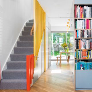 Open plan living space with stairs partitioned off with panels painted in bright yellow