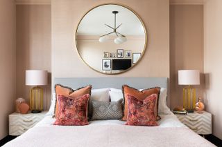 Double bed in neutral room with large mirror above headboard