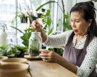 Woman makes terrarium inside a mason jar