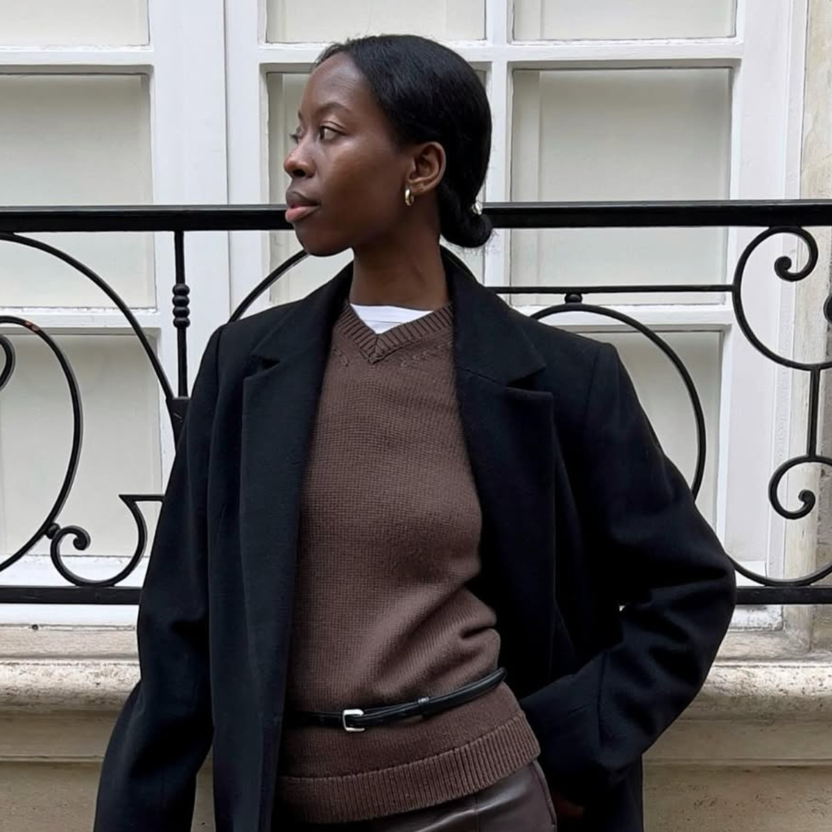 Sylvie in a brown V-neck jumper and black coat