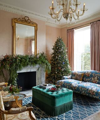 Elegant living room with fireplace dressed with foliage, christmas tree, blue patterned sofa, green ottoman
