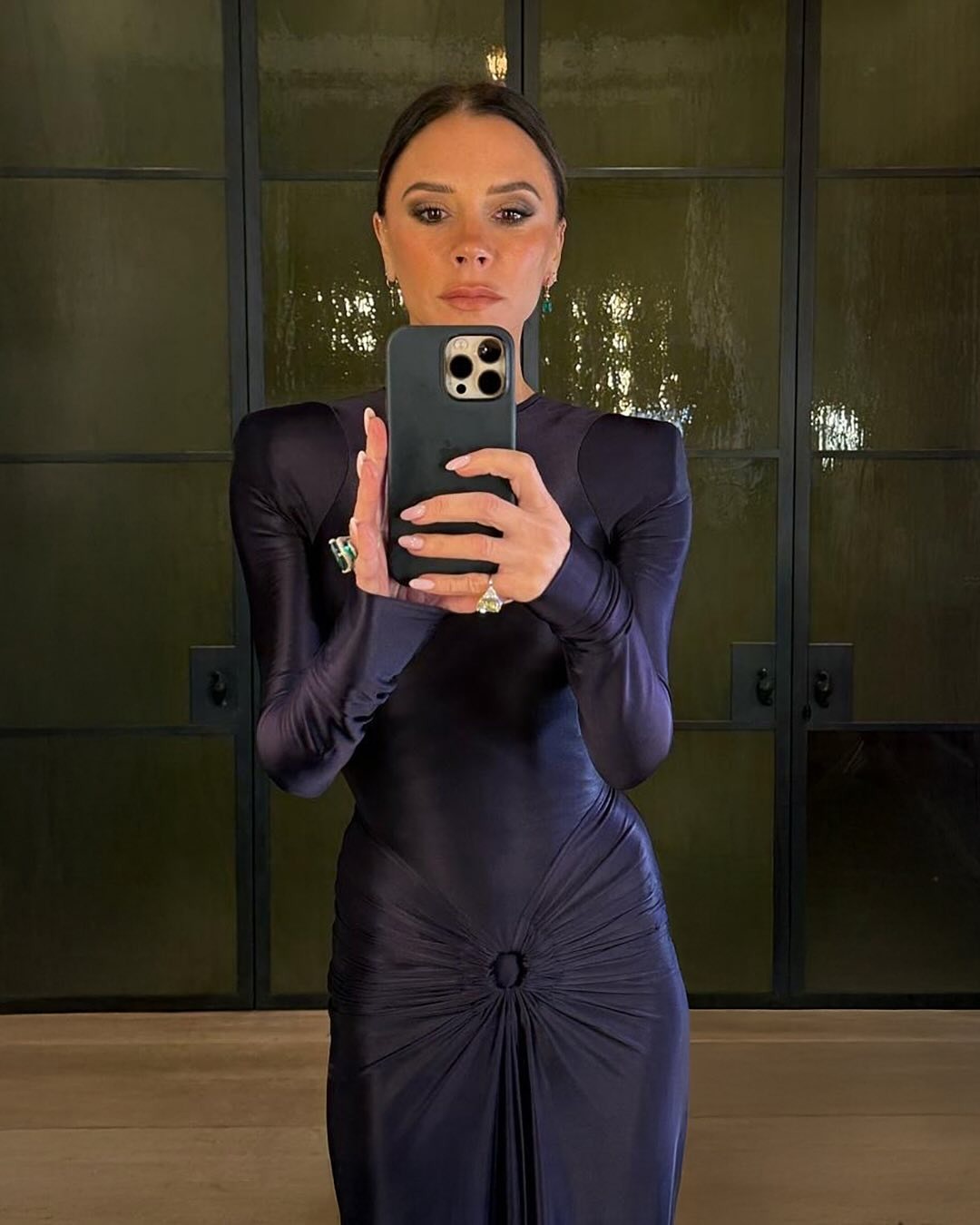 Victoria Beckham taking a selfie in a purple dress with a brown smoky eye
