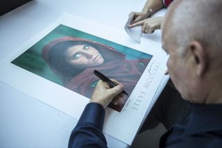  Steve McCurry signs a copy of his most famous photo Afghan Girl (Photo by Mustafa Kamaci/Anadolu Agency/Getty Images)