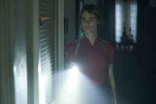Mackenzie Davis as Kirsten, holding a flashlight in the dark, in Station Eleven