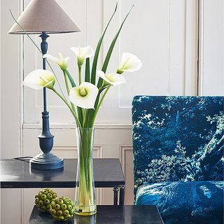 room with white door and blue sofa and table lamp and calla lilies