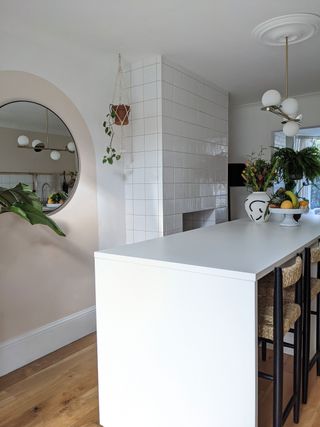 White kitchen island with round mirror on the wall and houseplants