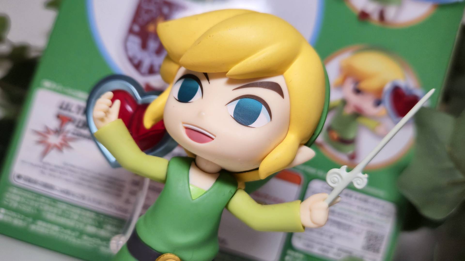 Close up of the Wind Waker Link nendoroid with a heart piece behind it.