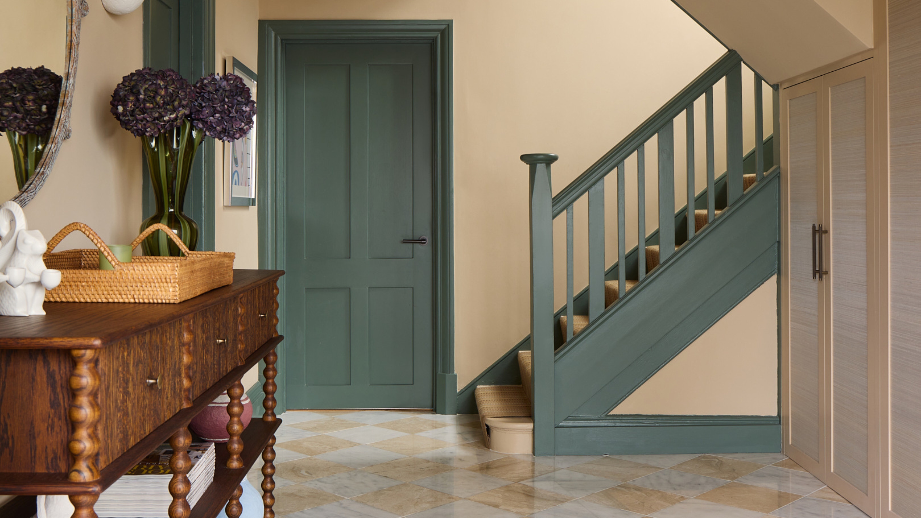 a hallway painted beige with green trim, basedboards, doors and architrave with a wooden console table