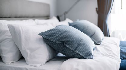 white pillows and blue cushions on a bed