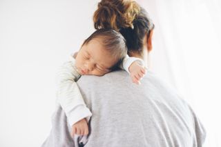 Newborn boy sleeping on mother's shoulder