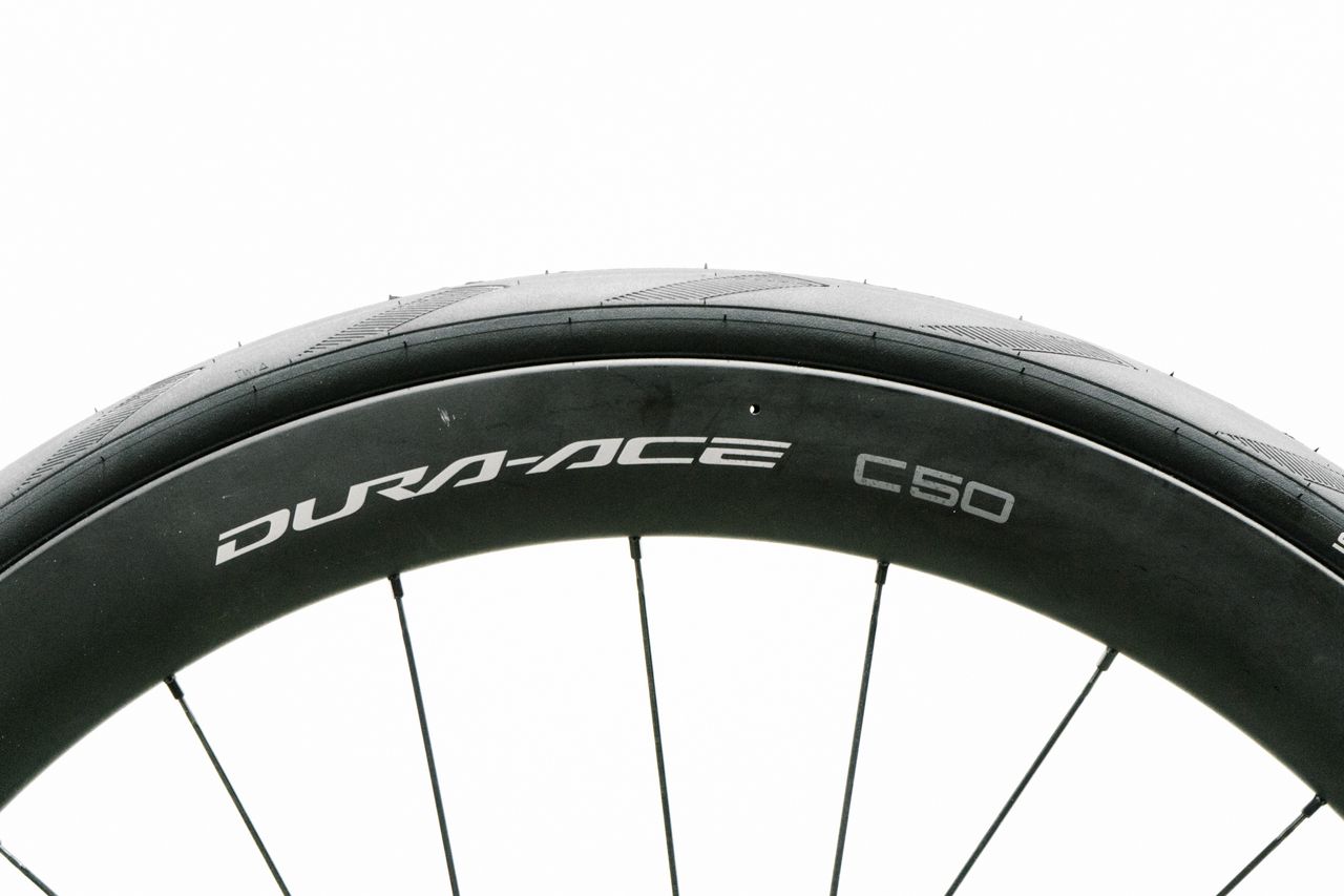 An aero road wheel stands against a white wall