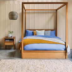 Wooden storage bed with denim duvet and mustard throw on polished floor with natural colour carpet