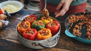 woman preparing stuffed peppers with rice and vegetables