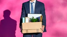 A businessman carries a box of belongings