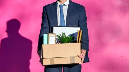 A businessman carries a box of belongings