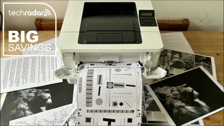 The HP LaserJet Pro 4001dn with a selection of mono print outs during our tests in a home office, next to a white TechRadar badge that reads 'Big Savings'