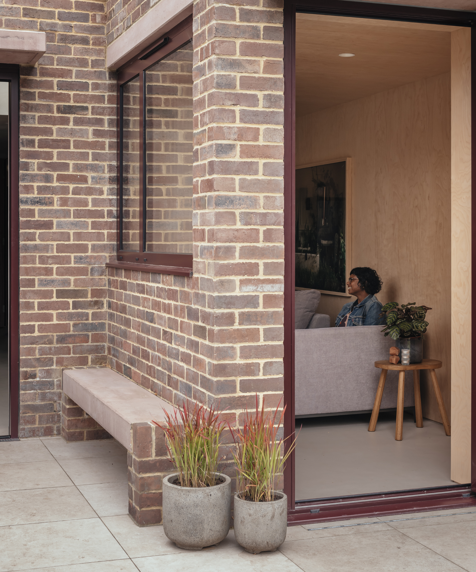 Close up of the exterior of the house and through a large window looking into sofa room