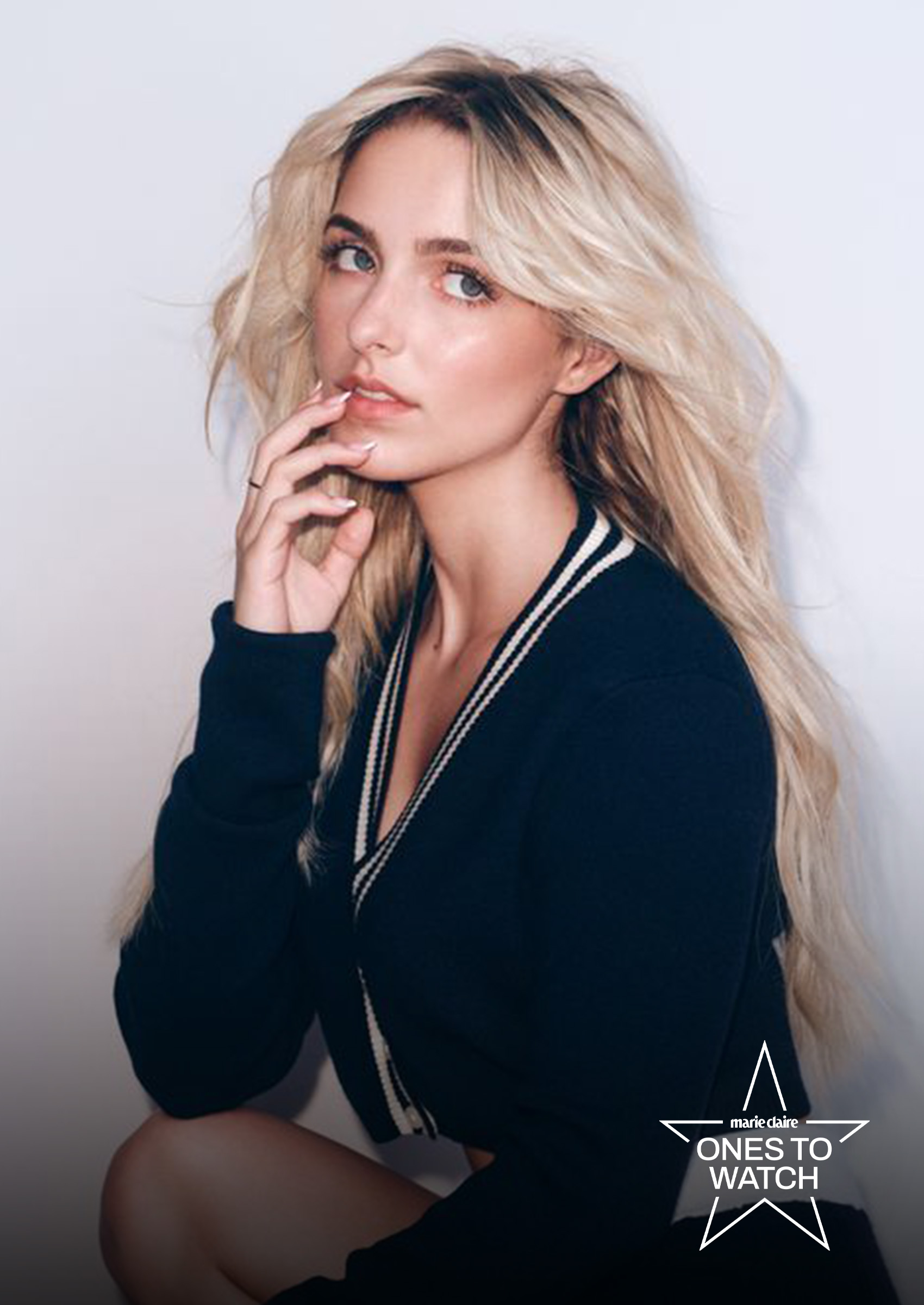 actress mckenna grace poses kneeling with her hand to her lips wearing a cardigan