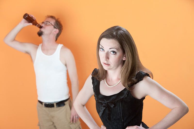 Unhappy Caucasian wife with alcoholic husband on orange background